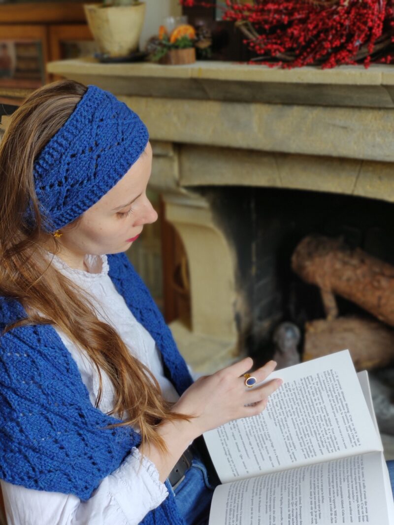 jeune femme assise en train de lire et portant une écharpe bleue et un headband assorti