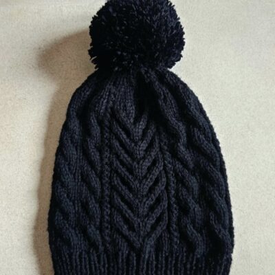 Bonnet noir à torsades et avec un pompon en laine mérinos de la marque Laine et Merveilles